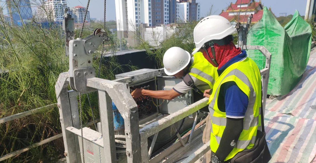 Workers inspecting a suspended platform control unit